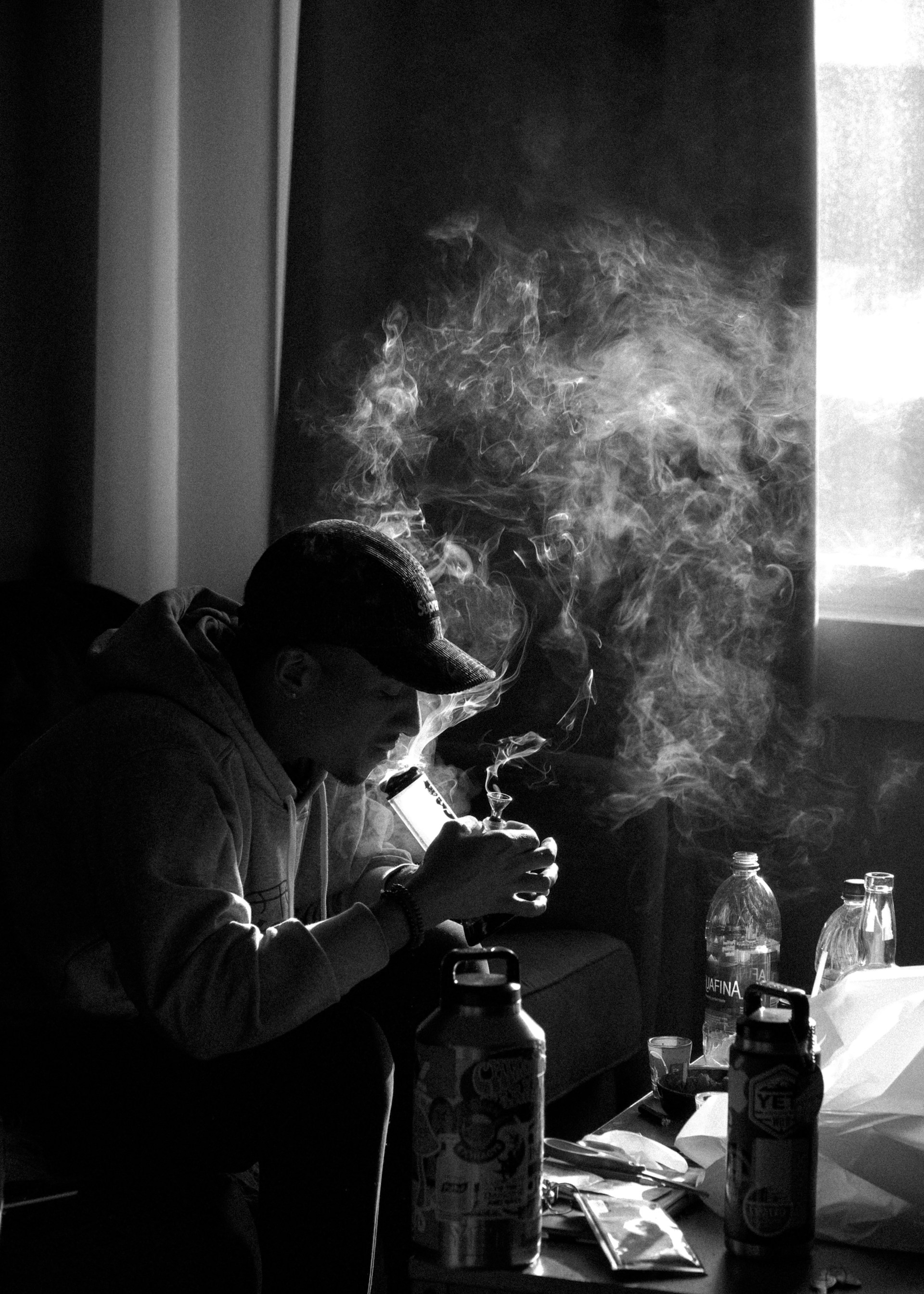 Man smokes bong, heavy exhale (b&w) (photo by Kevin Turcios)